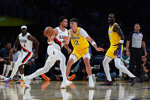 Portland Trail Blazers forward Toumani Camara, center left, is defended by Los Angeles Lakers forward Jake LaRavia (12) during the first half of an NBA basketball game in Los Angeles.