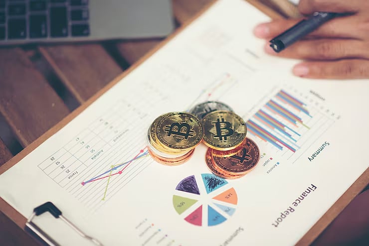 Stacks of Bitcoin and other crypto coins on a financial report with charts and graphs.