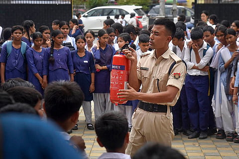 Fire safety drill at Guwahati school: A firefighter demonstrates the use of a fire extinguisher to students during an emergency mock drill, at a school, in Guwahati, Assam.