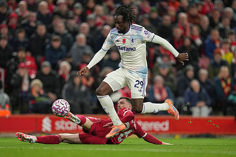 Aston Villa's Evann Guessand challenges for the ball with Liverpool's Andrew Robertson, bottom, during the English Premier League soccer match between Liverpool and Aston Villa in Liverpool, England.