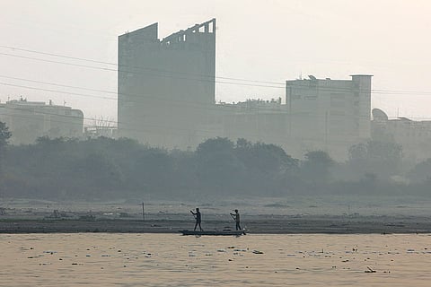 Men row a boat on the Yamuna river as a layer of smog engulfs the city amid deterioration in air quality in Delhi-NCR, in New Delhi.