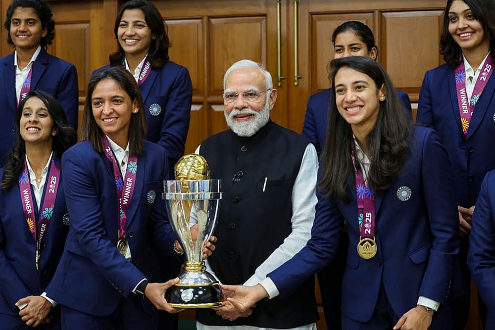 | Photo: Handout via PTI  : Prime Minister Narendra Modi holding the ICC Women's Cricket World Cup winner's trophy as he poses for a photograph with the winning Indian women cricket team in New Delhi. 