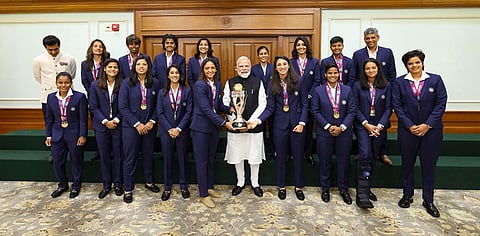 In this image, Prime Minister Narendra Modi holding the ICC Women's Cricket World Cup winner's trophy as he poses for a photograph with the winning Indian women cricket team in New Delhi.