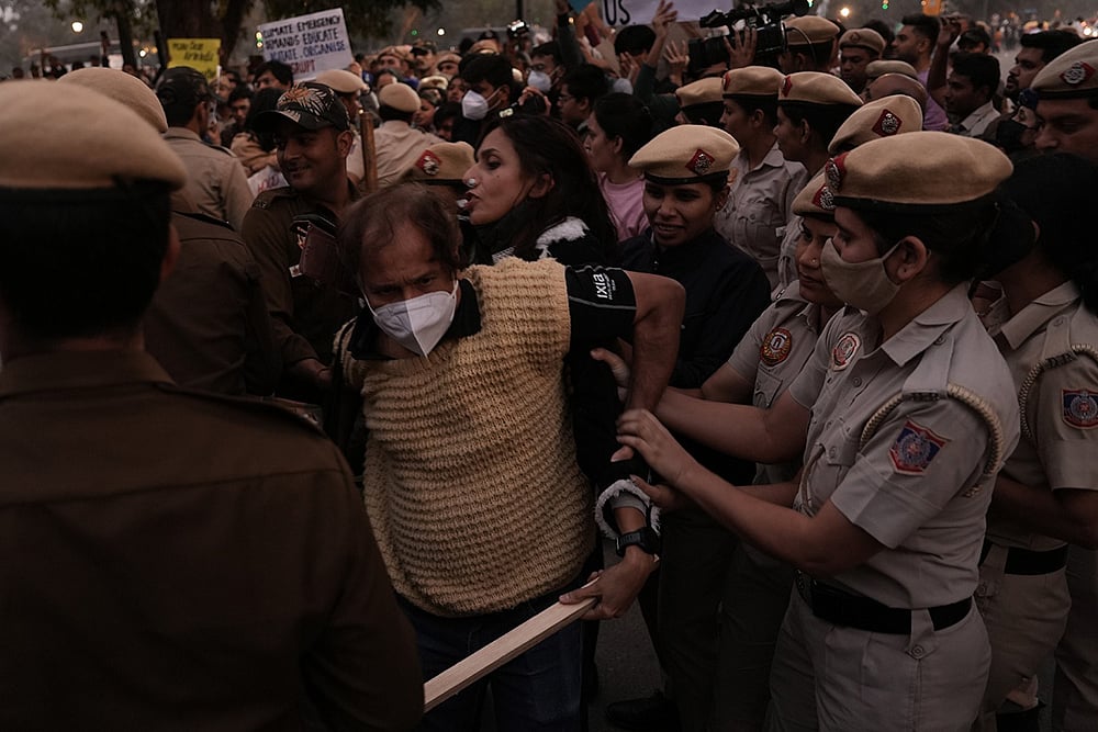Police detain activists during a protest near India Gate