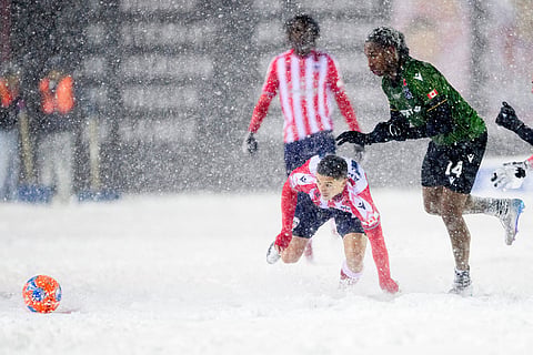 Atletico Ottawa's Manuel Aparicio (10) losses his footing in the snow as Cavalry FC's Caniggia Elva (14) runs for the ball during second half Canadian Premier League finals soccer action in Ottawa.