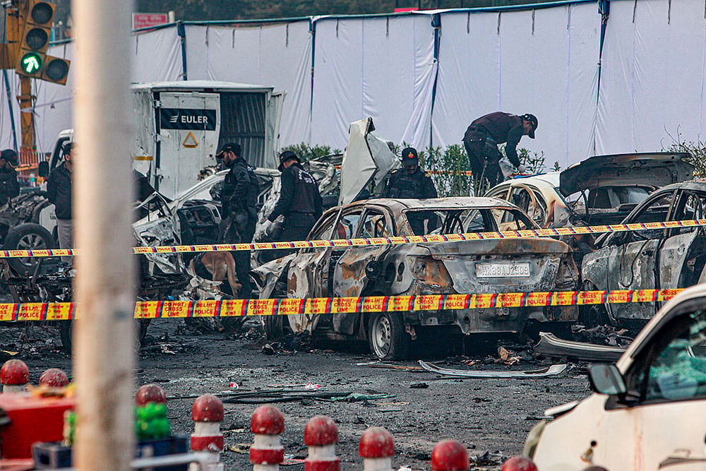 | Photo: PTI : Charred remains of vehicles at a cordoned off area following a blast that occurred near Red Fort Metro Station on Monday, killing at least nine people and gutting several vehicles, in New Delhi.