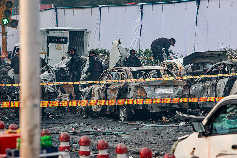 Photo: PTI : Charred remains of vehicles at a cordoned off area following a blast that occurred near Red Fort Metro Station on Monday, killing at least nine people and gutting several vehicles, in New Delhi.