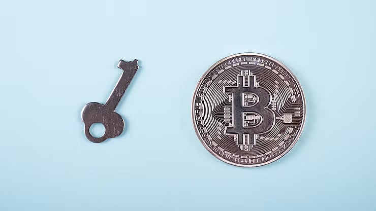A small key and a Bitcoin coin (BTC) on a light blue background, symbolizing private keys.