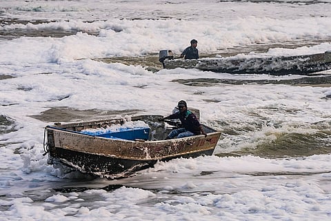 People ride boats in the polluted Yamuna river, in New Delhi.