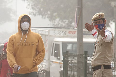 A pedestrian and a traffic policeman wear masks as air quality continues to deteriorate in Delhi-NCR, in Gurugram. Delhi's air quality remained in the 'severe' category for the third consecutive day, according to officials.