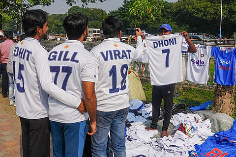 Cricket fans take selfies as they buy jerseys on the eve of the first Test cricket match of a series between India and South Africa, near Eden Gardens in Kolkata.