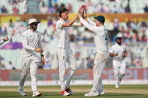 South Africa's Marco Jansen, center, celebrates with teammate Simon Harmer after the dismissal of India's Kuldeep Yadav on the second day of the first cricket test match between India and South Africa in Kolkata.