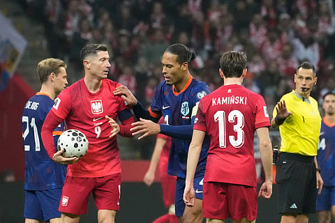 Netherlands' Virgil van Dijk, center, tries to get the ball from Poland's Robert Lewandowski while the game is interrupted during a World Cup 2026 group G qualifying soccer match between Poland and the Netherlands in Warsaw.
