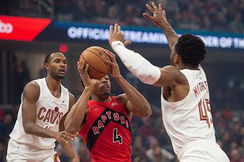 Toronto Raptors' Scottie Barnes (4) prepares to shoot as Cleveland Cavaliers' Donovan Mitchell (45) defends and Evan Mobley, rear looks on during the first half of an NBA basketball game in Cleveland.