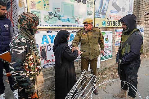A woman seeks permission from a policeman to enter a blocked road leading to the Nowgam police station, where an accidental explosion occured late Friday night, in Srinagar.