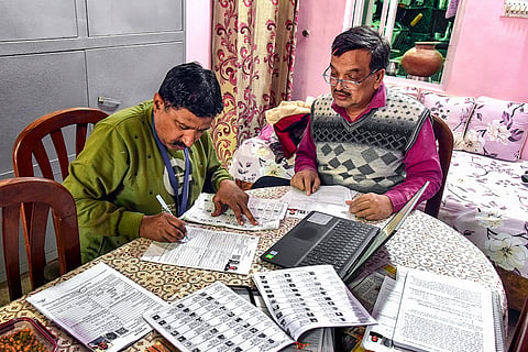 A Booth Level Officer (BLO) assists a voter in filling out the enumeration form for the special intensive revision (SIR) of electoral rolls, in Bikaner, Rajasthan.