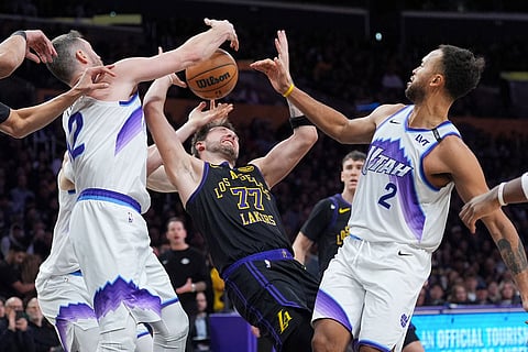 Los Angeles Lakers guard Luka Doncic (77) fights for a rebound with Utah Jazz forward Kyle Anderson (2) and forward Kevin Love (42) during the second half of an NBA basketball game in Los Angeles.