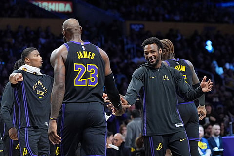 Los Angeles Lakers forward LeBron James (23) is greeted by guard Bronny James during a timeout in an NBA basketball game against the Utah Jazz in Los Angeles. 