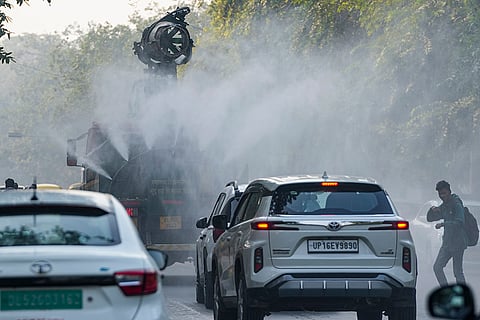 An 'anti-smog' vehicle sprays water mist to settle down particulate matter as other vehicles ply the road, amid poor air quality, in New Delhi.