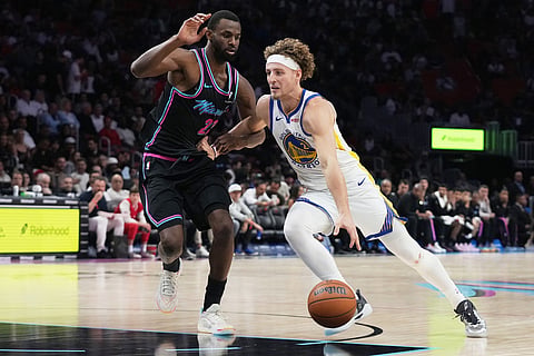 Golden State Warriors guard Brandin Podziemski, right, drives to the basket as Miami Heat forward Andrew Wiggins, left, defends during the second half of an NBA basketball game in Miami. 