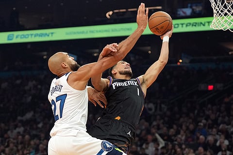 Phoenix Suns guard Devin Booker, right, drives past Minnesota Timberwolves center Rudy Gobert (27) during the first half of an NBA Cup basketball game, in Phoenix.