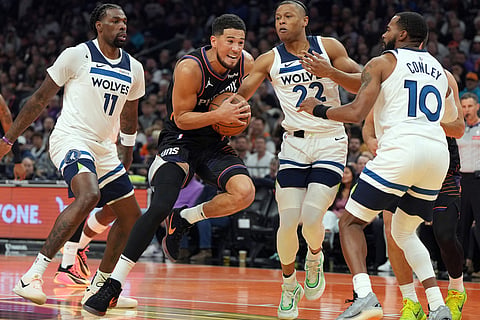 Phoenix Suns guard Devin Booker, second from left, drives between Minnesota Timberwolves center Naz Reid (11), guard Jaylen Clark (22) and guard Mike Conley during the first half of an NBA Cup basketball game in Phoenix. 
