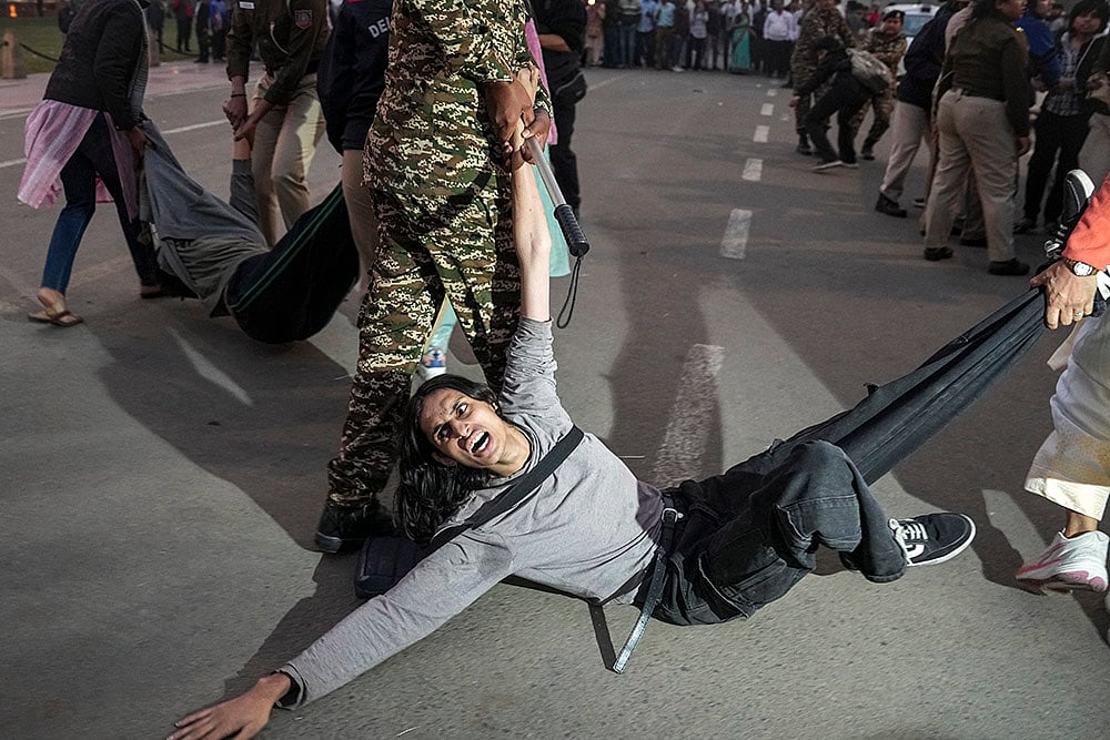 | Photo: PTI/Karma Bhutia : A protester being detained by security personnel during a protest against worsening air quality in the national capital, near the India Gate, in New Delhi. The air quality remained in the "very poor" category on Sunday morning, with the overall Air Quality Index (AQI) recorded at 381, according to the Central Pollution Control Board (CPCB). 