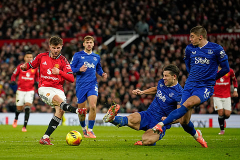 Manchester United's Mason Mount, left, takes a shot during the English Premier League soccer match between Manchester United and Everton in Manchester, England.