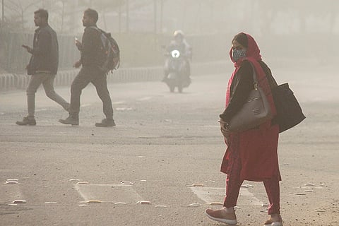 Commuters make their way amid low-visibility as air quality remains poor, in Gurugram.