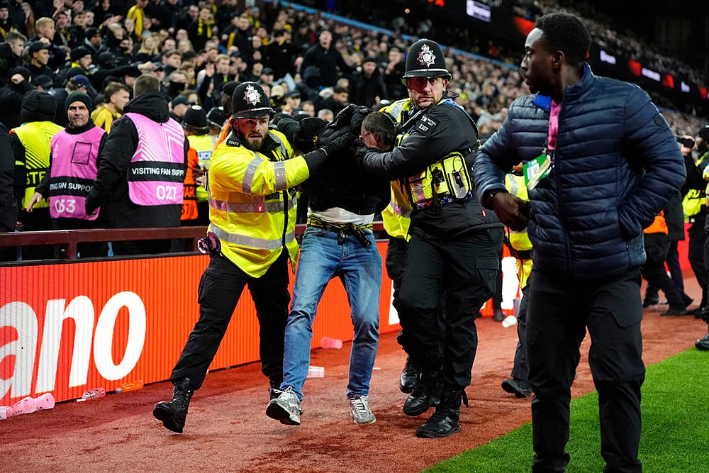 | Photo: Nick Potts/PA via AP : A Young Boys fan is escorted from the stadium by police during the Europa League soccer match between Aston Villa and Young Boys in Birmingham, England.