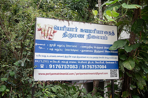 An advertisement board for the Periyar Matrimony platform promotes unions beyond caste and faith, while also supporting divorcee and widow remarriages. 