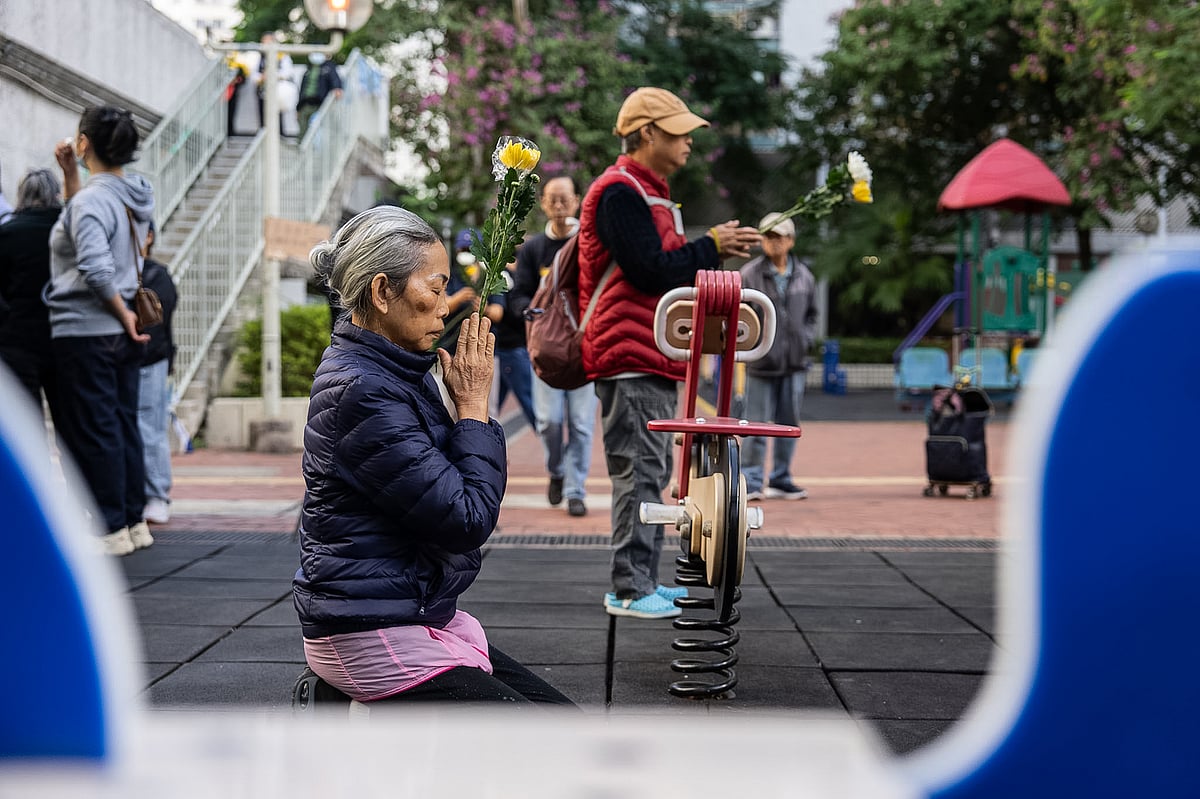Chan Long Hei : People holds flowers and prays near the scene after the deadly fire that started Wednesday at Wang Fuk Court, a residential estate in the Tai Po district of Hong Kong's New Territories, Saturday Nov. 29, 2025. 