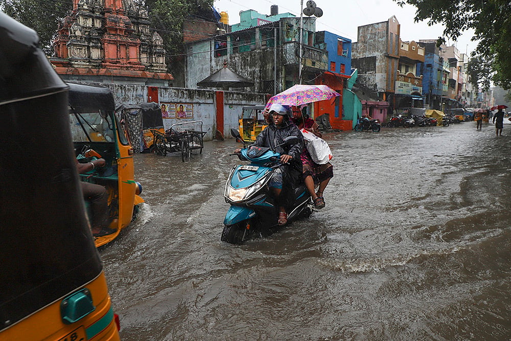 | Photo: PTI/R Senthilkumar : People wade through waterlogged road amid heavy rainfall in the wake of Cyclone Ditwah, in Chennai.