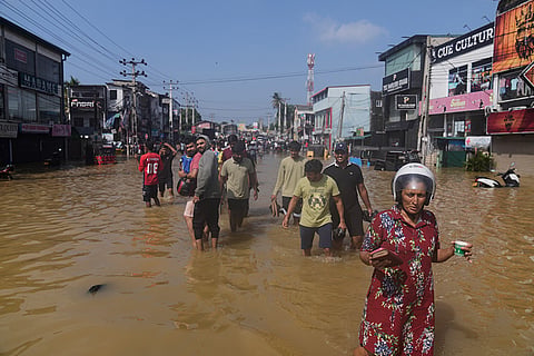 People wade through a submerged area of Colombo, Sri Lanka, following flooding.