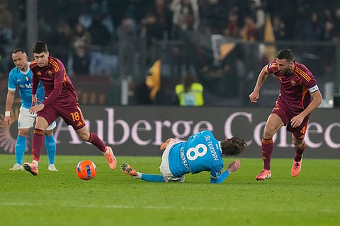 Napoli's Scott McTominay, centre, falls flanked by Roma's Bryan Cristante, right, and Roma's Matias Soule during the Serie A soccer match between Roma and Napoli in Rome.