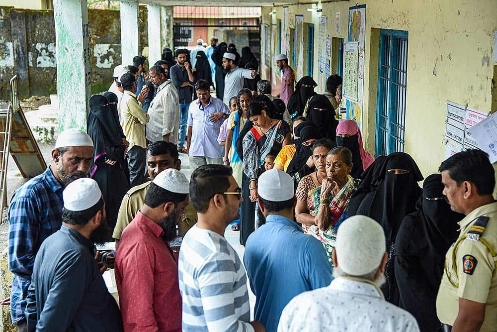 People wait in a queue to cast their votes at a polling booth during the Maharashtra local body elections, at Taloja, in Navi Mumbai. - Photo: PTI