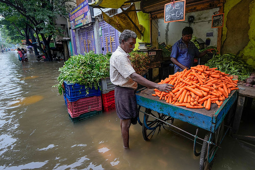 Photo: PTI/R Senthil Kumar : A man shops for vegetable on a waterlogged street following Cyclone Ditwah, in Chennai.