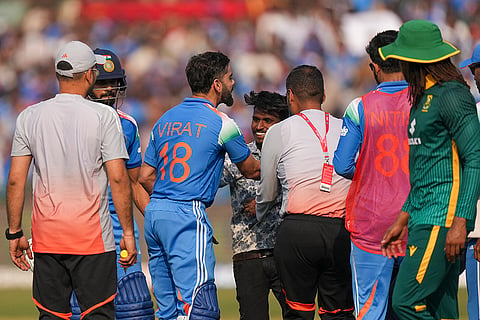 India's Virat Kohli, center, being greeted by a pitch invader between overs during the second ODI cricket match of a series between India and South Africa, at Shaheed Veer Narayan Singh International Stadium, in Raipur, Chhattisgarh. 
