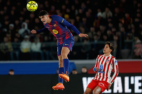 Barcelona's Pedri jumps for the ball during a Spanish La Liga soccer match between Barcelona and Atletico de Madrid, in Barcelona, Spain.