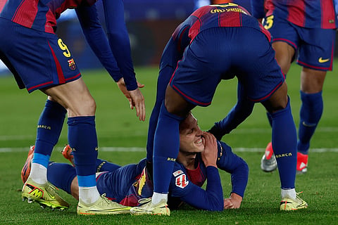 Barcelona's Dani Olmo reacts in pain in his arm after scoring his side's second goal during a Spanish La Liga soccer match between Barcelona and Atletico de Madrid, in Barcelona, Spain.