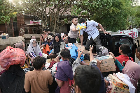 Volunteers distribute relief goods to survivors at a village affected by flash flood in Pidie Jaya, Aceh province, Indonesia.