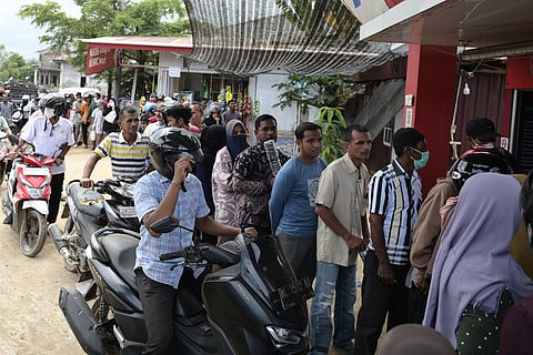 People who are affected by floods queue up for fuel at a gas station in Pidie Jaya, Aceh province, Indonesia.