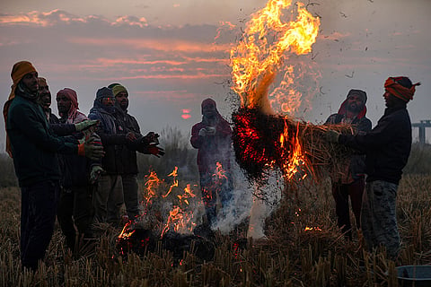 Farmers warm themselves around burning stubble on a winter morning during sunrise near the India-Pakistan International border, at Ranbir Singh Pura, in Jammu district.