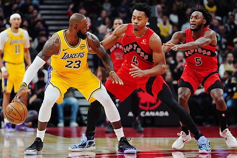 Los Angeles Lakers' LeBron James (23) protects the ball from Toronto Raptors' Scottie Barnes (4) and Immanuel Quickley (5) during first-half NBA basketball game action in Toronto.