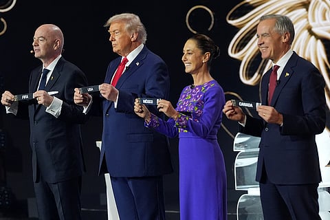 Canadian Prime Minister Mark Carney, Mexican President Claudia Sheinbaum, President Donald Trump and FIFA President Gianni Infantino hold up country names during the draw for the 2026 soccer World Cup at the Kennedy Center in Washington.