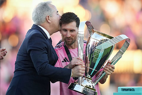 Inter Miami's Lionel Messi, centre, holds the trophy and receives a kiss on the head from managing owner Jorge Mas after defeating the Vancouver Whitecaps during the MLS Cup final soccer match, in Fort Lauderdale, Fla.