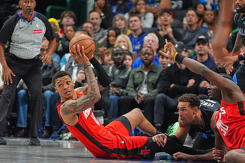 Houston Rockets forward Jabari Smith Jr.. front left, looks to pass from the floor against Dallas Mavericks forward Dwight Powell, second from bottom right, during the second half of an NBA basketball game in Dallas.