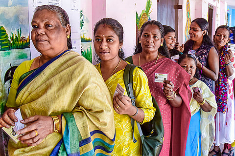 Voters wait in a queue to cast their votes at a polling booth during the first phase of the Kerala local body elections, in Kochi.