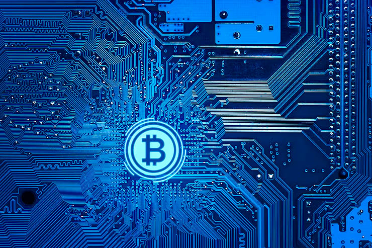 Bitcoin symbol over a blue circuit board background.