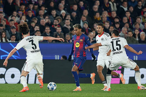 Barcelona's Lamine Yamal, runs with the ball among Frankfurt's Arthur Theate, left, and Frankfurt's Ellyes Skhiri during the Champions League opening phase soccer match between Barcelona and Eintracht Frankfurt in Barcelona, Spain.
